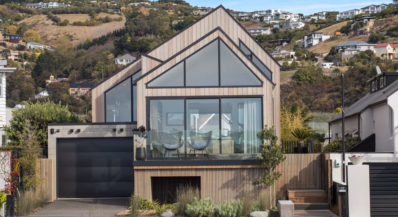 Beachville by Site Architecture, oiled cedar cladding and asymmetrical roofline set against the red cliffs of Te Raekura Christchurch.