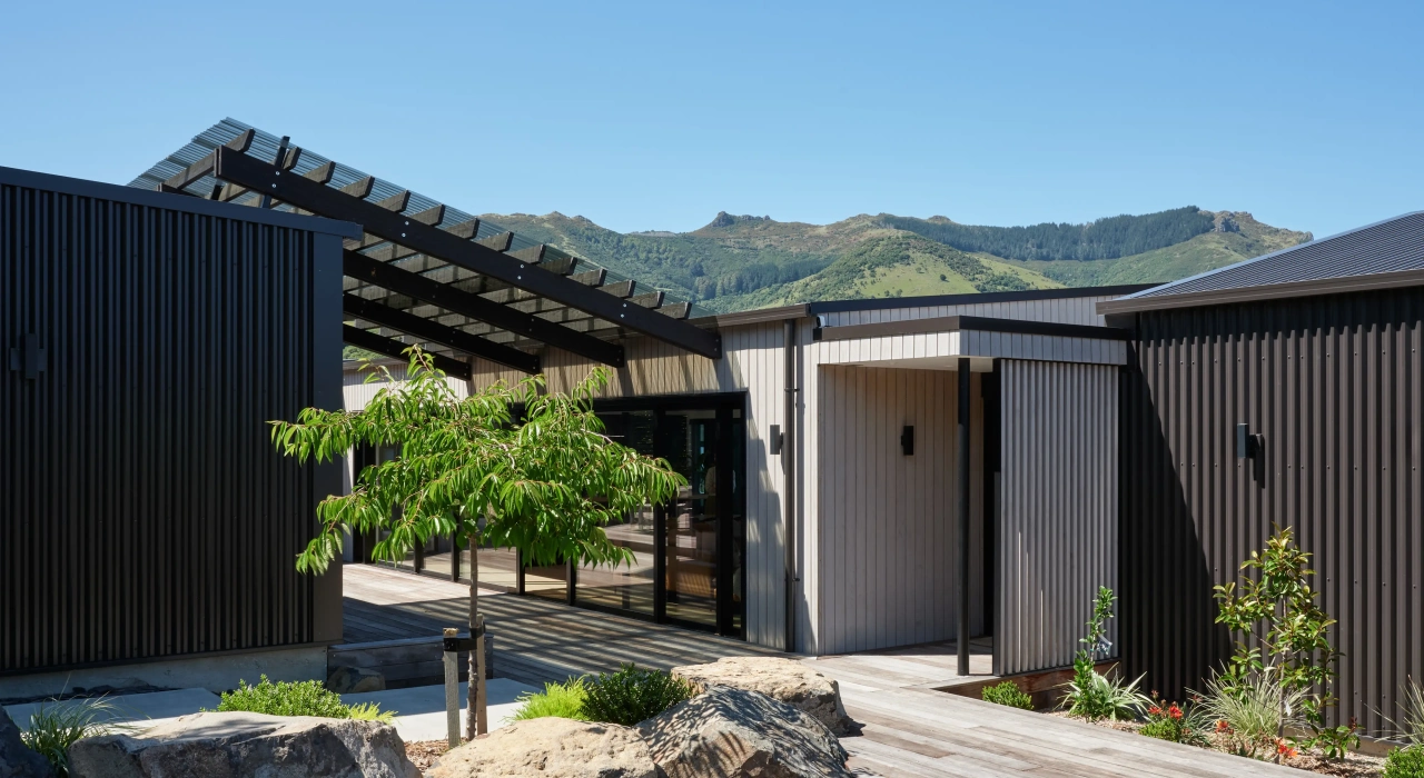 <img alt="Entry pergola at Akaroa Pentref. Dark clad forms with mature trees and timber deck, Site Architecture, Banks Peninsula." src="/images/e/n/t/r/y/entry-and-pergola-akaroa-pentref-photo-site-architecture-srp-fec49d72.webp?description" width="4000" height="3000" />