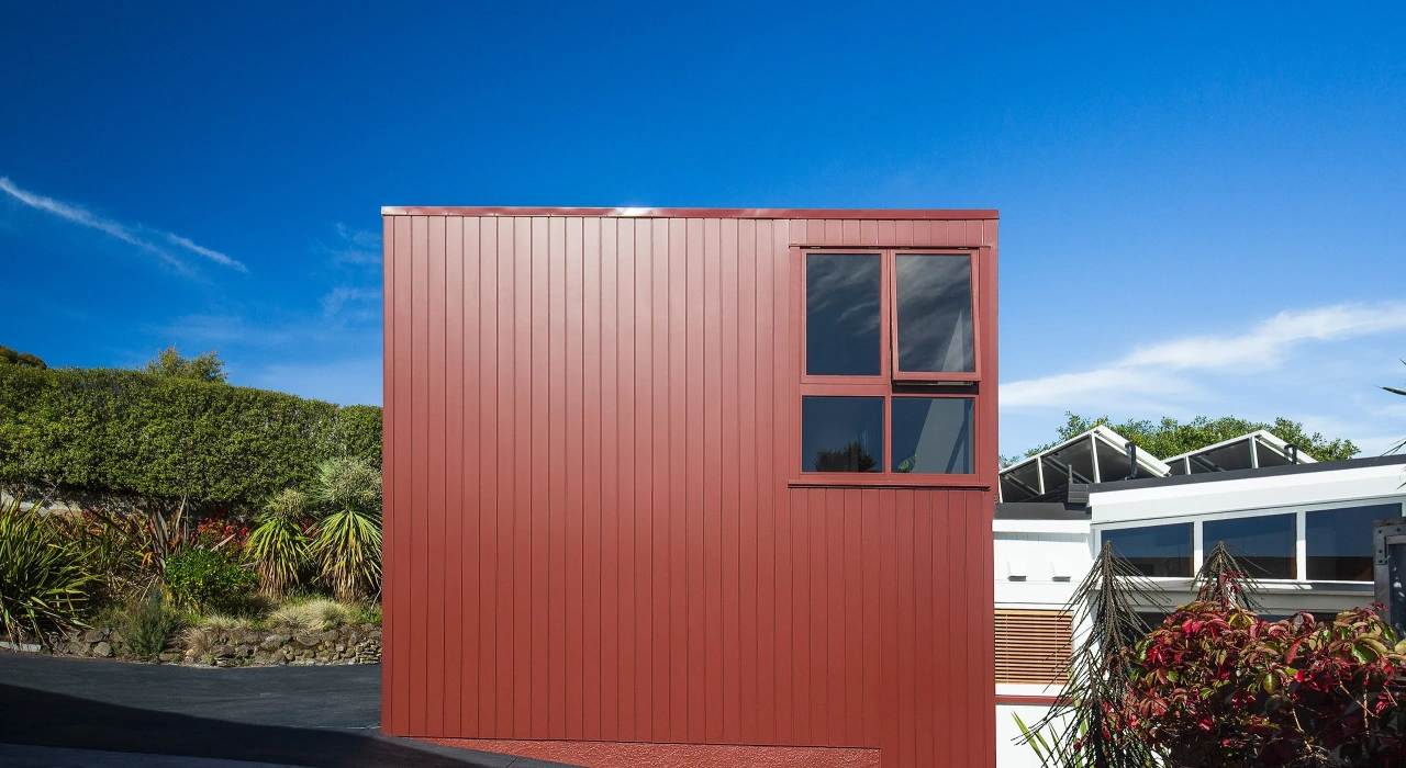 <img alt="Exterior detail of red Coloursteel cladding with small square window, set among established garden planting." src="/images/s/i/t/e/-/site-architects-interior-architecture-modernist8-95745082.webp?description" width="2560" height="1707" />