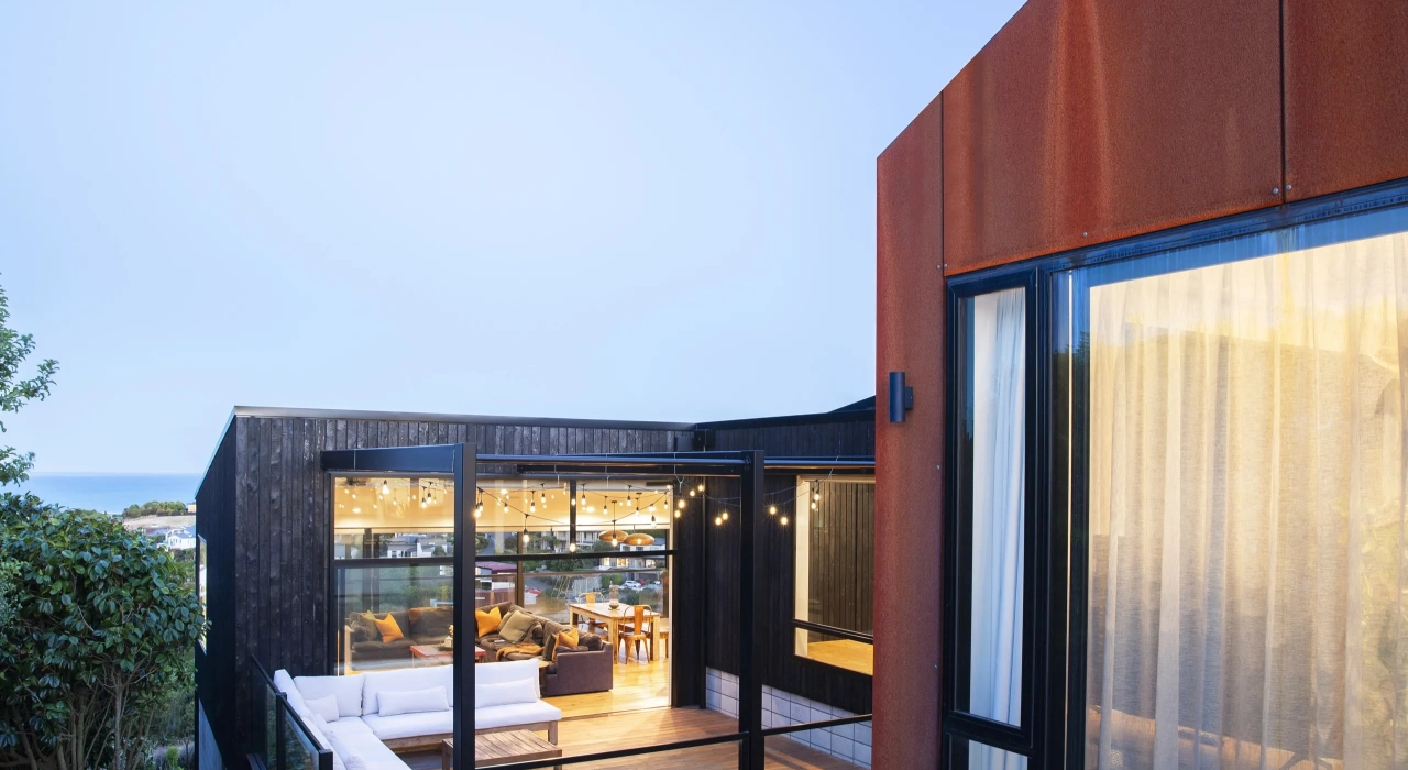 <img alt="Sheltered courtyard at evening, corten steel framing interior light with views to the hills and sea beyond." src="/images/s/i/t/e/-/site-architecture-drayton-drive10-599c9bc1.webp?description" width="2560" height="1706" />