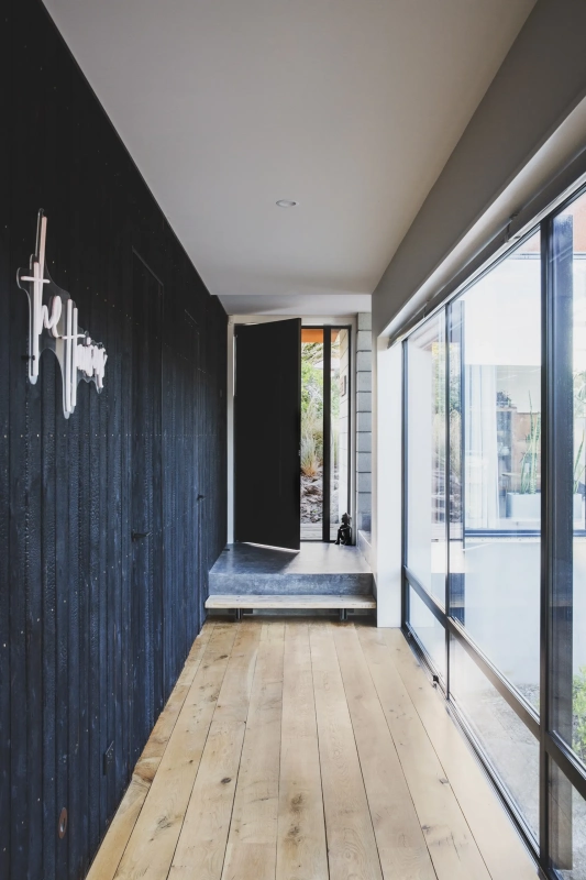 <img alt="Dark entry corridor with natural light filtering through glazing, charred larch cladding and raw blockwork detail." src="/images/s/i/t/e/-/site-architecture-drayton-drive5-061400f4.webp?description" width="1706" height="2560" />