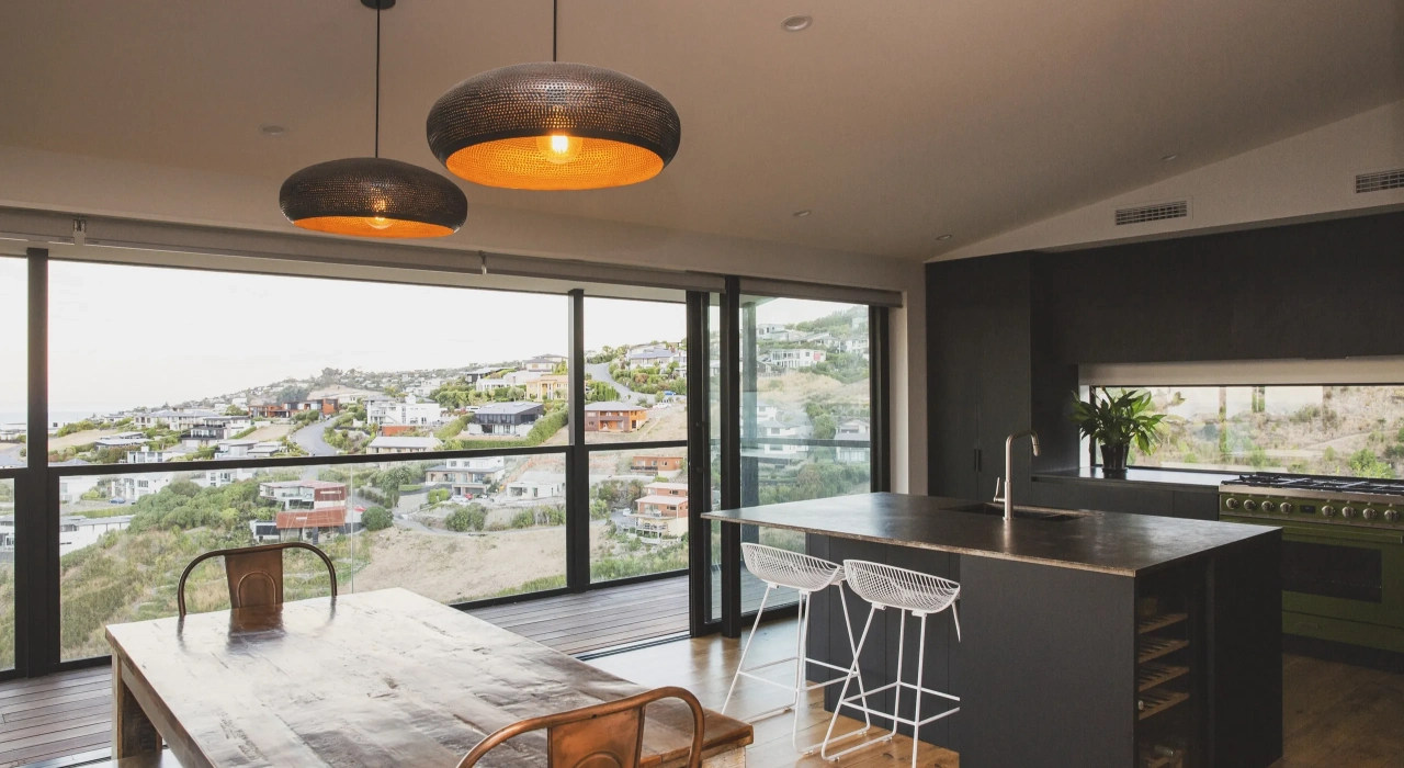 <img alt="Open-plan kitchen and dining with pendant lighting and full-height glazing framing views over the surrounding hills." src="/images/s/i/t/e/-/site-architecture-drayton-drive6-5a7a6505.webp?description" width="2560" height="1706" />