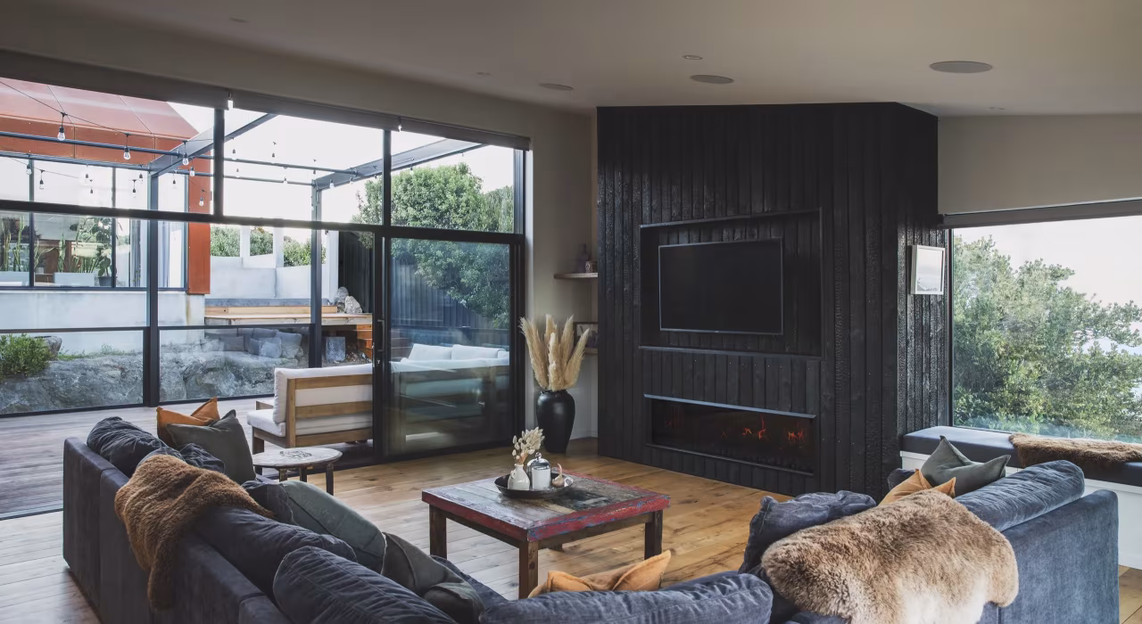 <img alt="Living area with dark joinery, timber flooring and expansive glazing bringing in the hillside landscape." src="/images/s/i/t/e/-/site-architecture-drayton-drive7-14a23d1e.webp" width="2560" height="1706" />