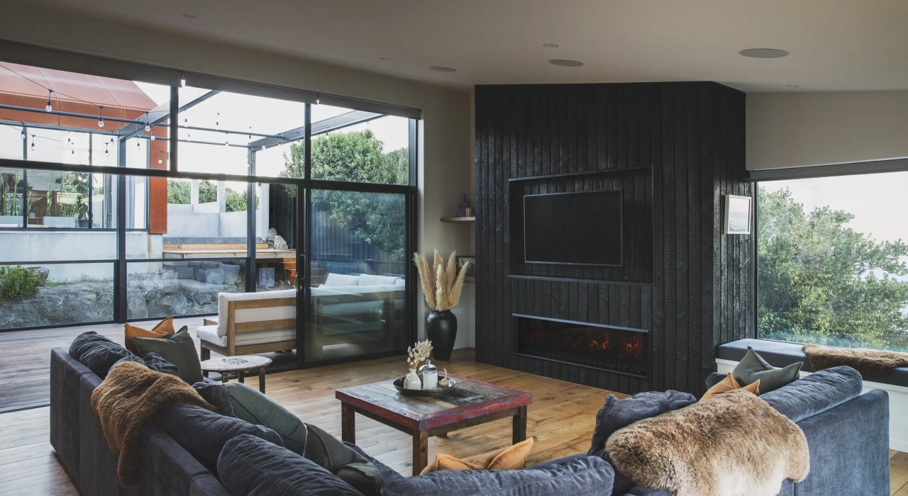 <img alt="Living area with dark joinery, timber flooring and expansive glazing bringing in the hillside landscape." src="/images/s/i/t/e/-/site-architecture-drayton-drive7-d8cb27eb.webp?description" width="2560" height="1706" />